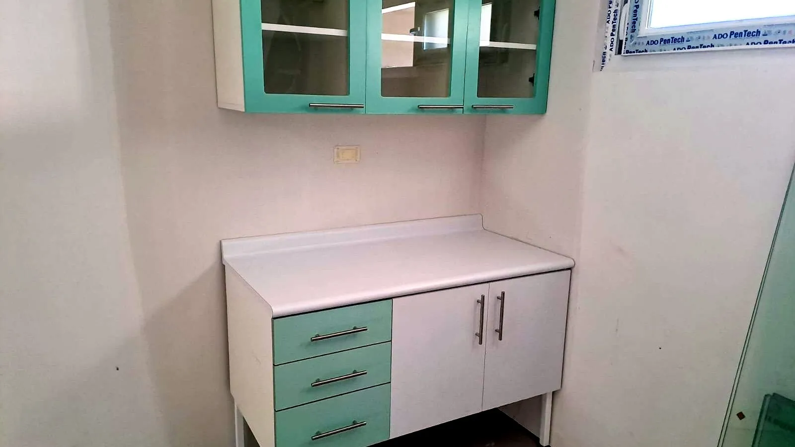 Mueble bajo con cubierta blanca y respaldo, cajonera verde agua y puertas blancas, bajo aéreos con puertas de vidrio y marco verde